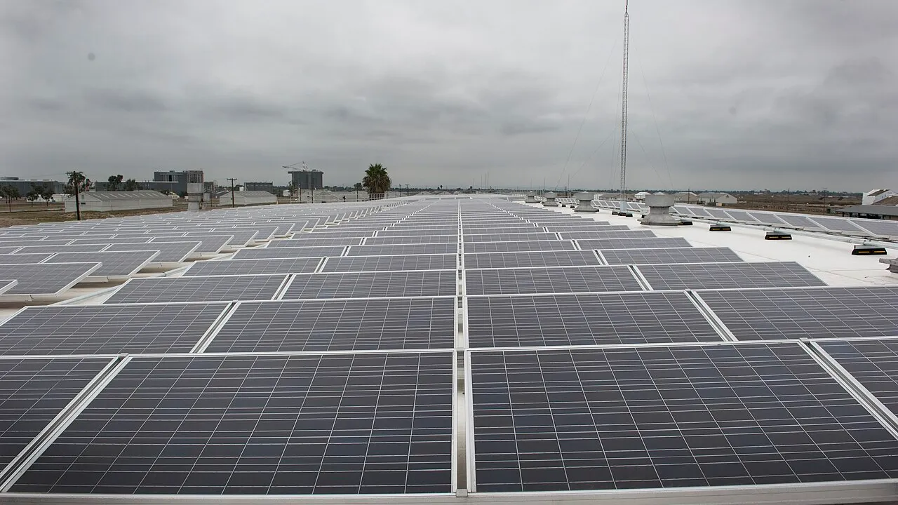 Grande arranjo de painéis solares instalados em telhado comercial sob céu nublado