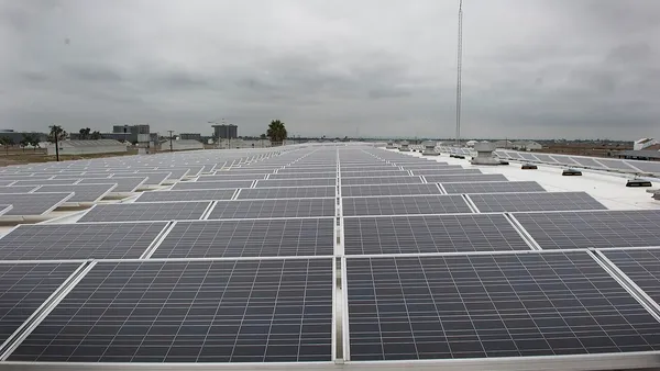 Grande arranjo de painéis solares instalados em telhado comercial sob céu nublado