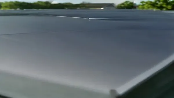 Painéis solares instalados no telhado de uma casa residencial com carro elétrico carregando na garagem