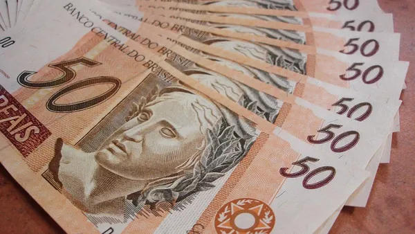 Notas brasileiras de real sobre mesa com calculadora e planilha de cálculo financeiro